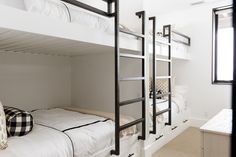 the bunk beds are all white and have black metal ladders on each one side