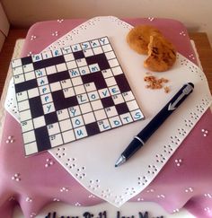 a birthday cake with a crossword puzzle on it and a pen next to it