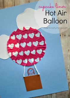 a hot air balloon made out of paper on a piece of blue paper with white hearts