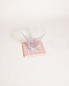 a glass bowl sitting on top of a pink tile coaster