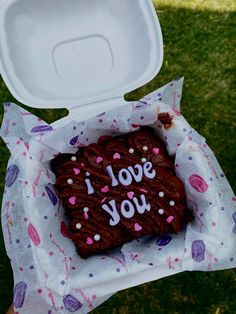 a heart shaped piece of chocolate cake with i love you written on it in a box