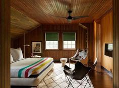 a bedroom with wood paneling and a bed in the corner next to a chair