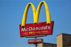 a mcdonald's drive thru sign is shown in front of a brick building and blue sky