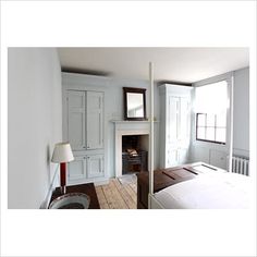 a bedroom with a bed, fireplace and white cabinets in it's center area