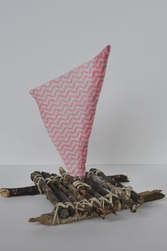 an origami kite sitting on top of some sticks and wood logs in front of a white wall