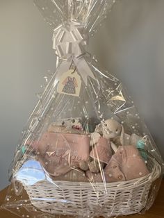 a white basket filled with lots of baby items on top of a wooden table next to a wall