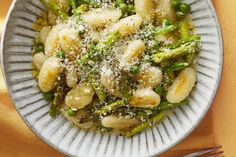 a white plate topped with pasta and asparagus covered in parmesan cheese