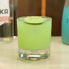 a green drink with a slice of lime on the rim