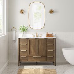 a bathroom with a sink, mirror and bathtub next to a rug on the floor