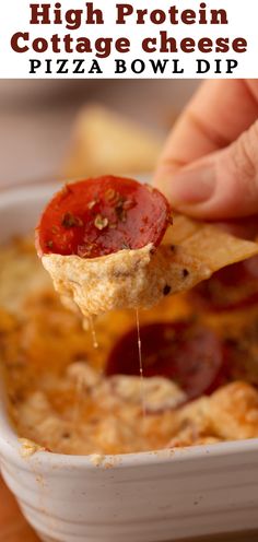 a hand holding a tortilla chip with cheese and pepperoni on it, over a bowl of pizza dip