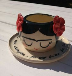 a ceramic cup and saucer decorated with flowers on a white wooden table top in the sun