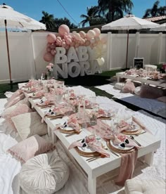 a baby shower is set up with pink and white balloons, plates and napkins