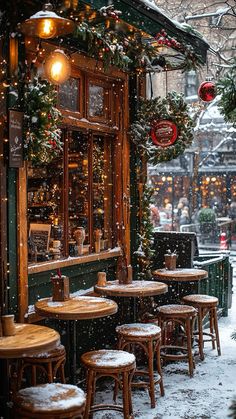 the outside of a restaurant with tables and chairs covered in snow, surrounded by christmas decorations