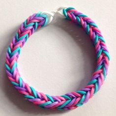 a close up of a colorful bracelet on a white table with a blue, pink and purple braid