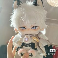 a cat doll with white hair and blue eyes holding it's paw up to the camera