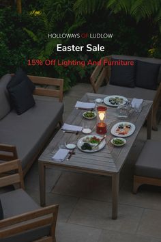 a table with plates of food on it in the middle of a patio surrounded by greenery