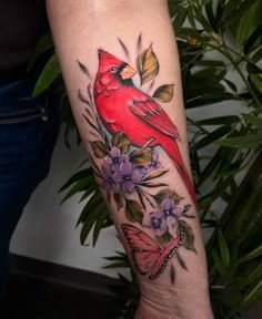 a woman's arm with a red bird and butterfly tattoo on the left forearm