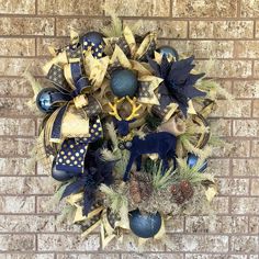 a wreath with blue and gold decorations hanging on a brick wall