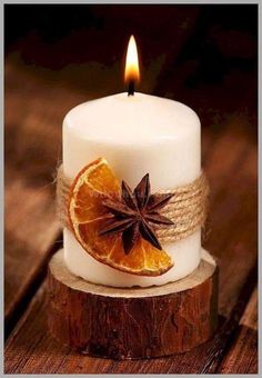 a white candle with an orange slice and star anise sitting on top of it