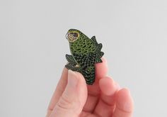 a small green bird sitting on top of a finger