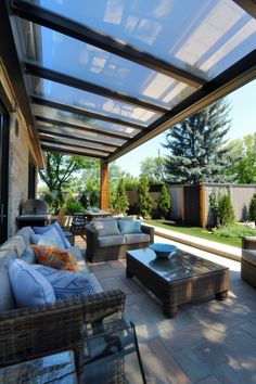 a covered patio with wicker furniture and blue pillows on the couches under an awning