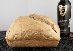 a loaf of bread sitting on top of a cooling rack next to a bottle of guinness