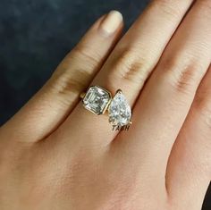 a woman's hand with two engagement rings on top of her finger and the other one has an oval shaped diamond in it