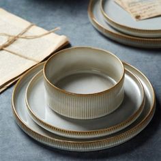 a table topped with white and gold dinnerware on top of a blue table cloth