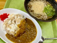 a plate with rice, meat and vegetables on it next to a bowl of noodles