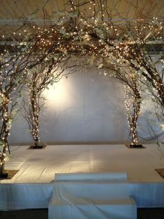 a white table topped with lots of trees covered in lights and branches on top of it