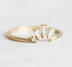 three stone ring in yellow gold on white tablecloth with small diamond cut stones around the band