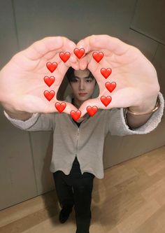 a woman is holding up her hands with red hearts on the palms in front of her face