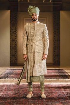 a man standing on top of a rug wearing a turban and green pants