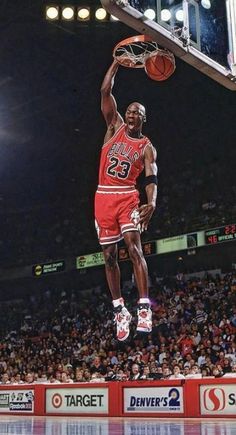 a basketball player dunking the ball in front of an arena full of people watching