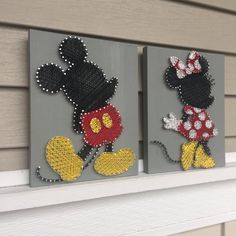 two mickey and minnie mouse paintings on a mantle