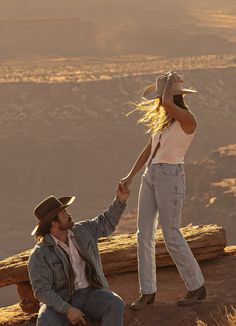 a man holding the hand of a woman on top of a mountain