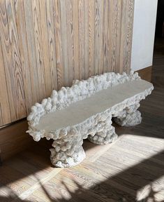 a white bench sitting on top of a hard wood floor next to a wooden wall