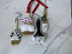 three christmas ornaments are hanging on a marble counter with red and white ribbons around them