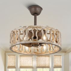 a chandelier hanging from the ceiling in a living room with windows and blinds