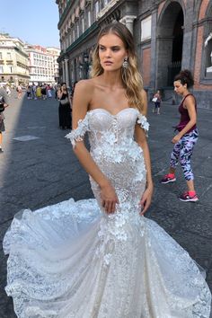 a woman in a wedding dress standing on the street