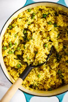 a pot full of rice and peas with a wooden spoon