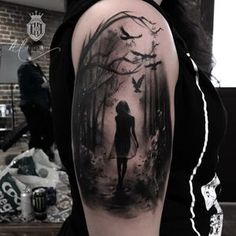 a woman with a black and white tattoo on her arm is walking through the woods