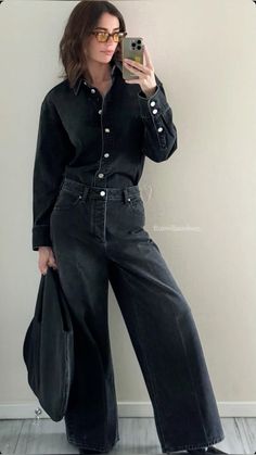 a woman taking a selfie with her cell phone while wearing black denim overalls