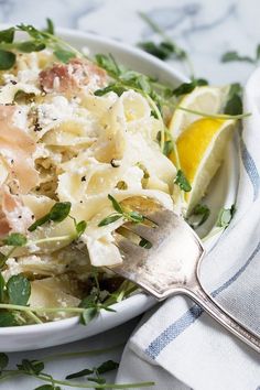 a white bowl filled with pasta and meat on top of a blue and white towel