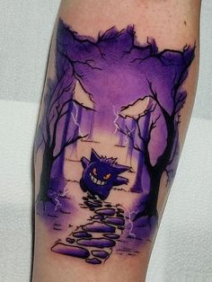 a man's arm with a cartoon character on it and a path leading into the woods