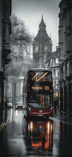 a red double decker bus driving down a rain soaked street in front of a clock tower