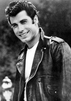 a black and white photo of a man in a leather jacket smiling at the camera