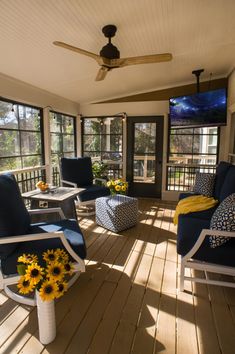 the sun shines through the windows onto a porch with blue chairs and yellow flowers