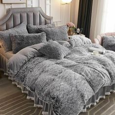 the bed is made with grey fur and pillows