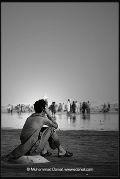 a man sitting on top of a beach next to the ocean